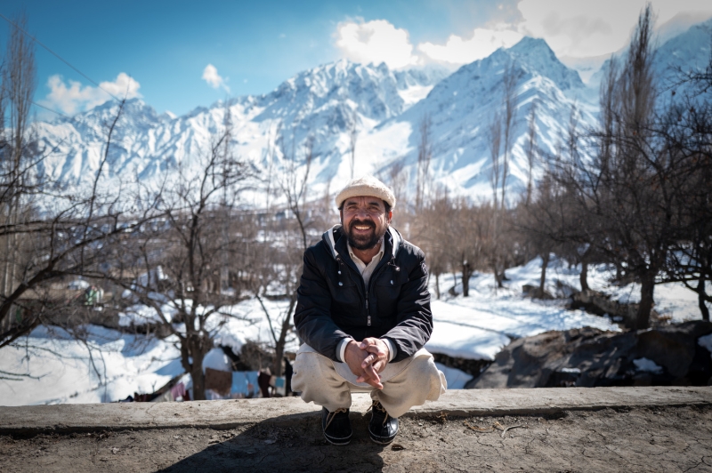 A man crouches in front of some mountains