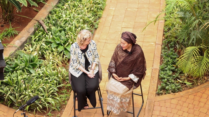 Two women seated outdoors in front of a microphone 
