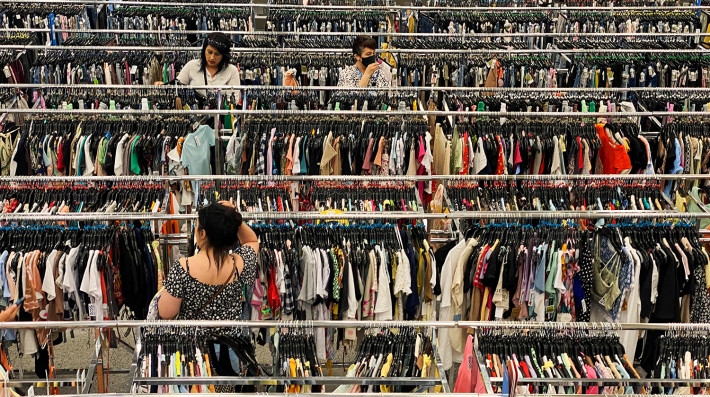 People browse racks of clothes in a department store
