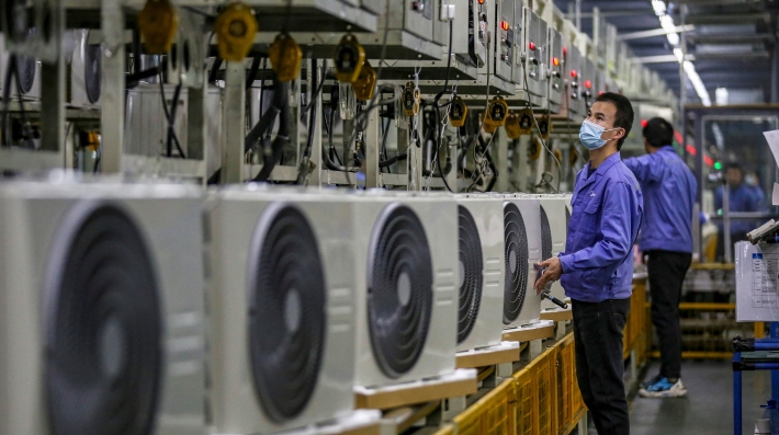 A factory worker looks at a row of airconiditoners