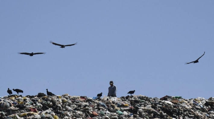 Waste picker sifts through garbage at a dump site