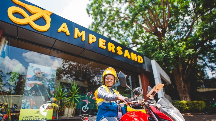 E-moto taxi driver Imigambi Jouyesse pose on her e-motorcycle by the Ampersand Headquarters in Kigali, Rwanda