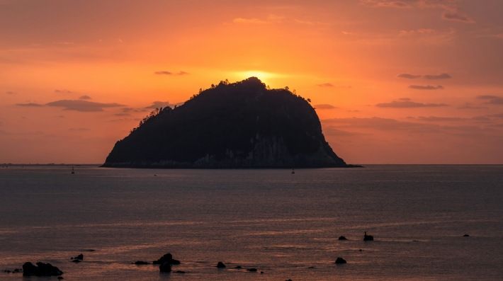 Silhouette of island on sea during sunset