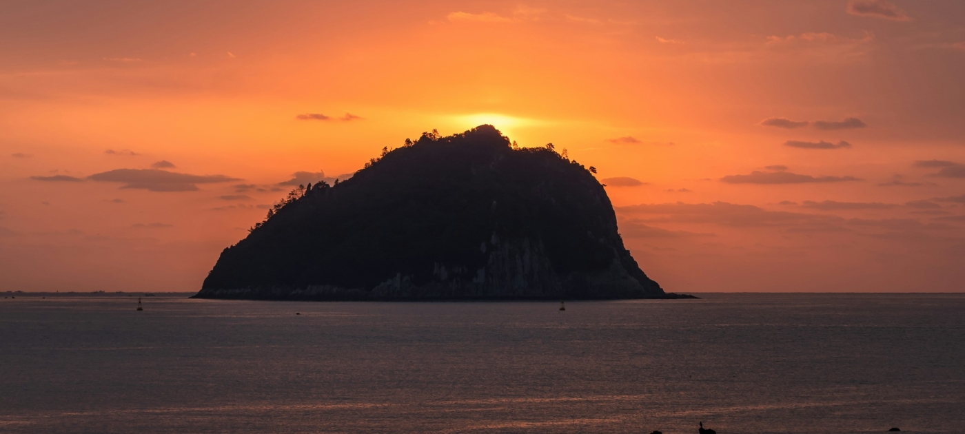Silhouette of island on sea during sunset
