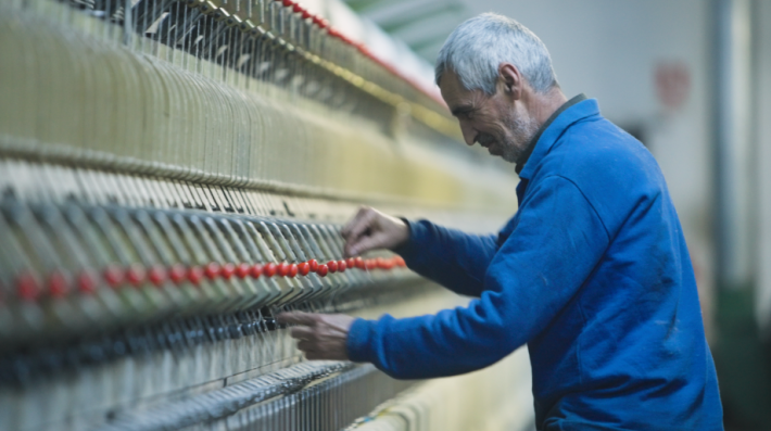 A man tending to a machine in a textiles factory 