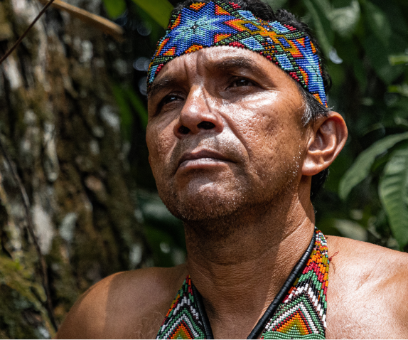 A man in a traditional headdress looking of into the distance 