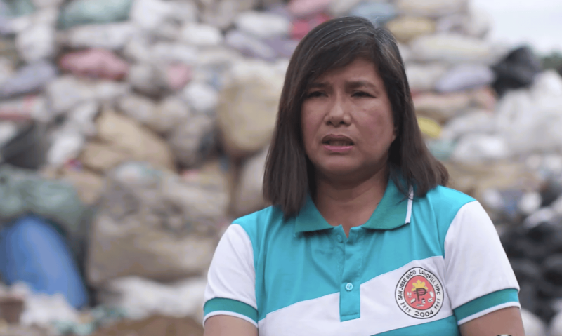 Woman with garbage pile in the background